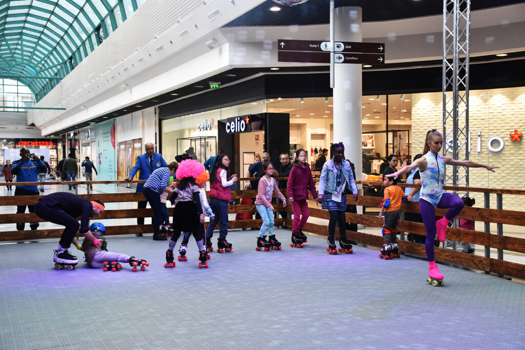 Enfants et adultes patinant en rollers sur une piste de roller disco dans une galerie marchande