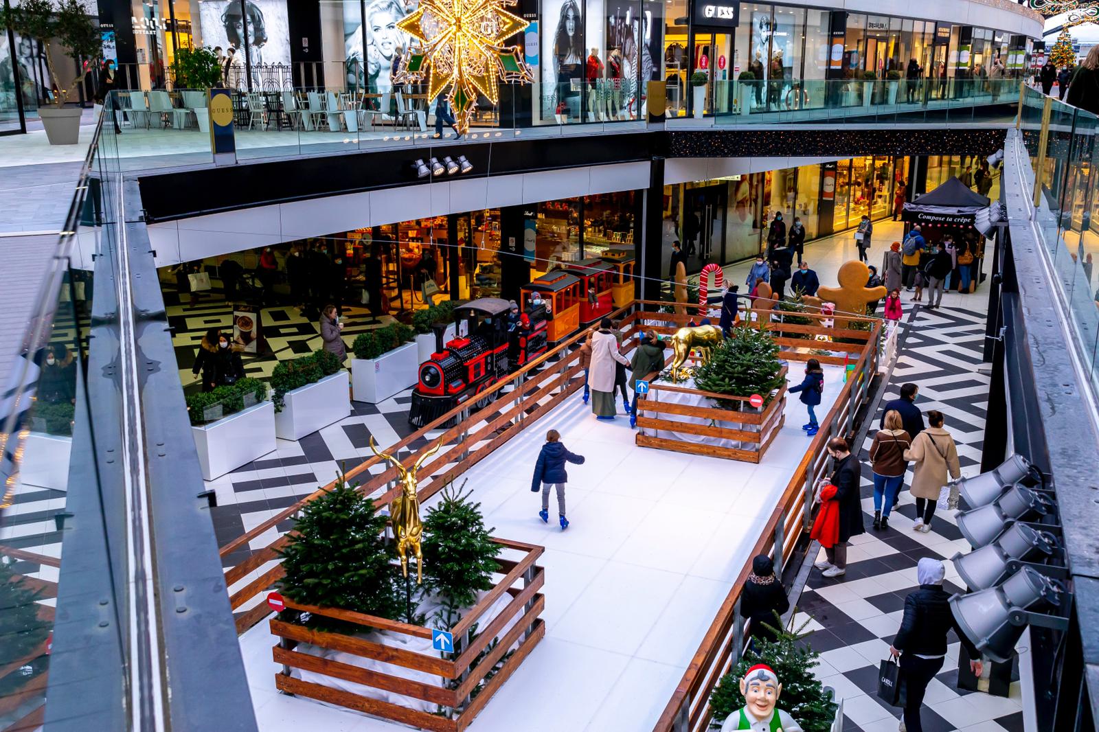 Patinoire synthétique dans un centre commercial entre des sapins