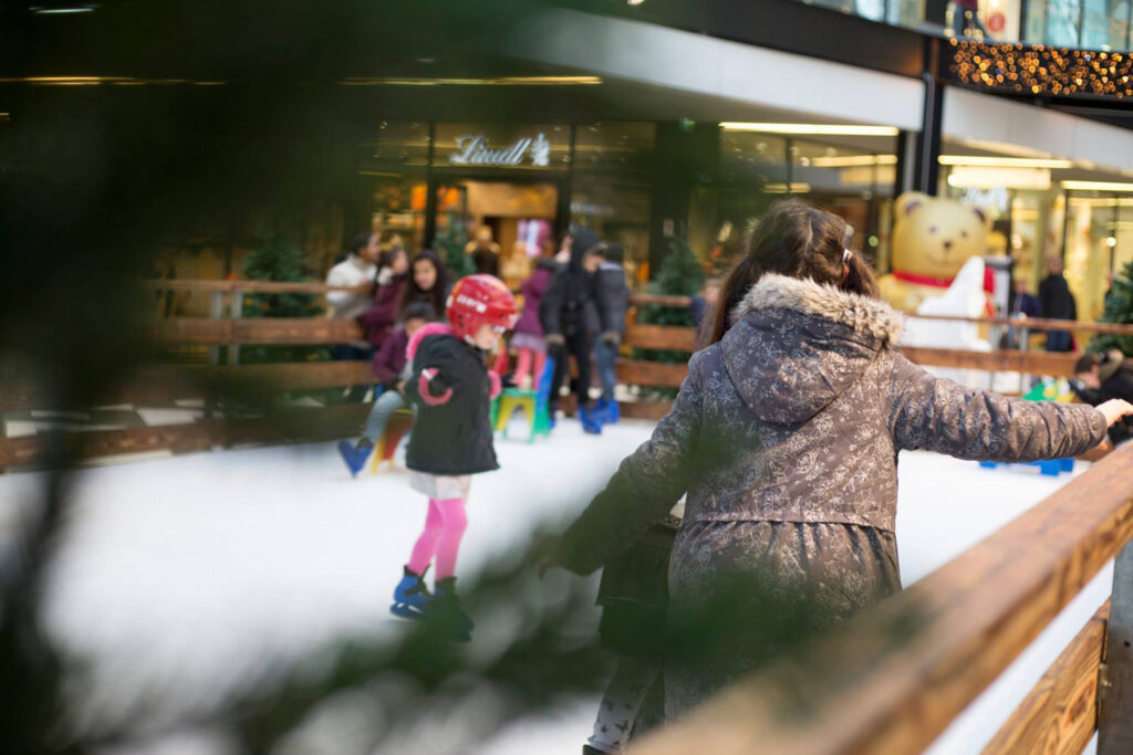 Patinoire synthétique dans une galerie marchande entre des branches de sapin